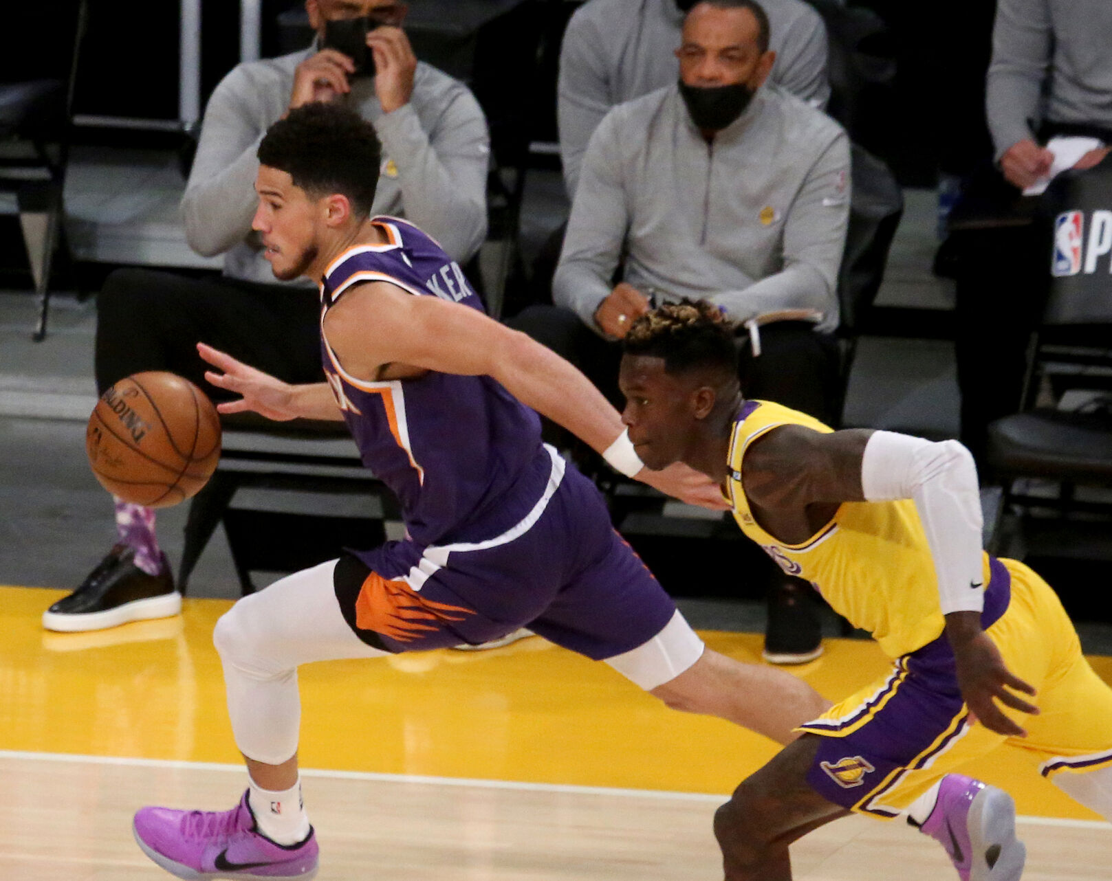 The Phoenix Suns' Devin Booker moves the ball ahead of the Los Angeles Lakers' Dennis Schroder during the first quarter in Game 6 of the Western Conference first-round series at Staples Center on Thursday, June 3, 2021 in Los Angeles.
